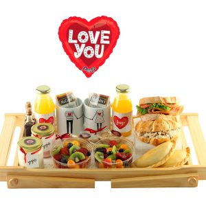 Desayuno sorpresa de aniversario para dos de Dulce Regalo. Bandeja de madera con patas plegable con dos tazas, dulces para compartir, jugos, café pasado, sandwiches, frutas, yogur, empanada, ideal para celebrar en pareja con entrega a domicilio en Lima.